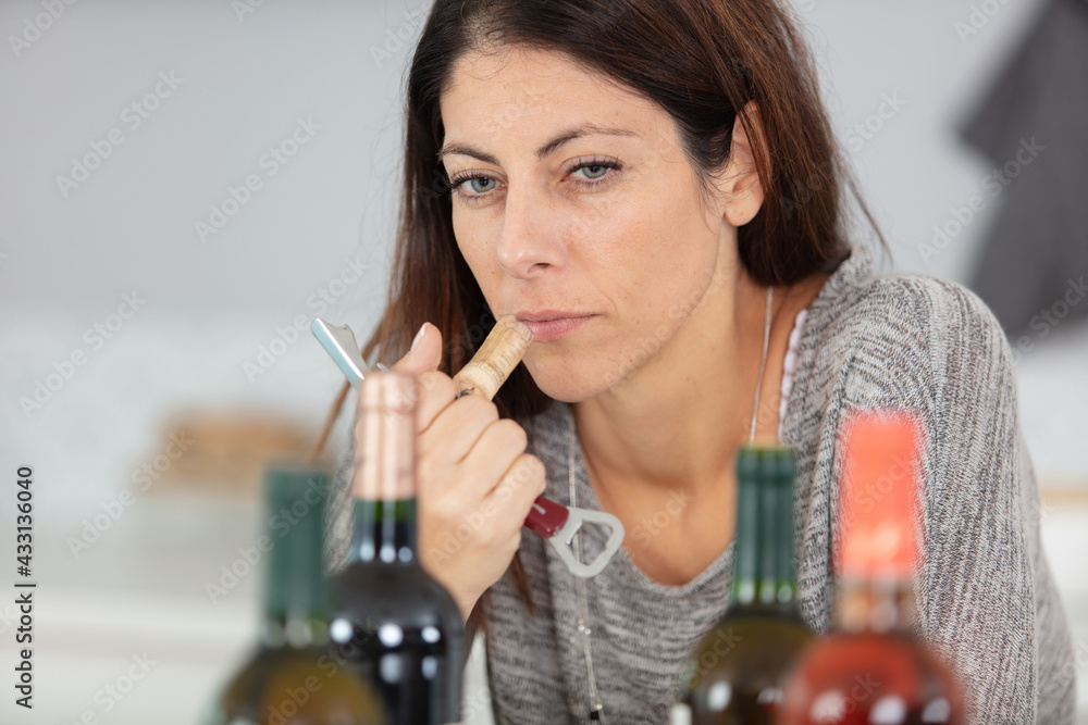 serious lady smelling wine cork - obrazy, fototapety, plakaty 