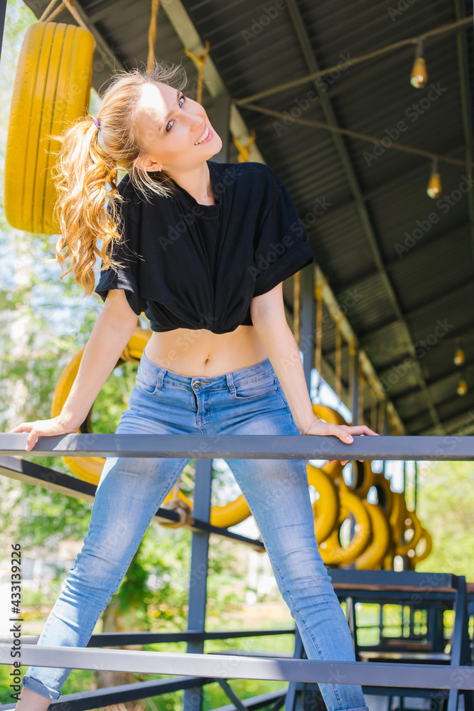 A young athletic girl stands smiling. Bright sunlight falls on the girl. A beautiful figure.