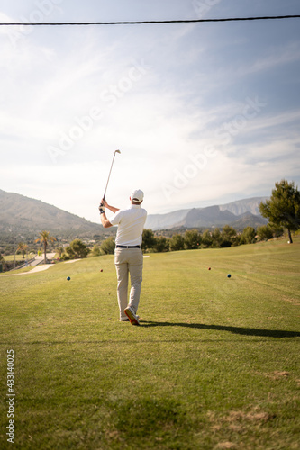 Golf player making a perfect swing on the golf course in the sunset.