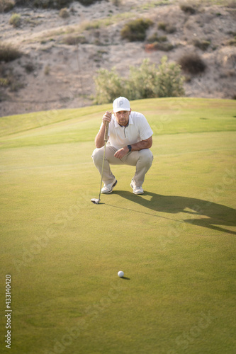 Golfer looking for the best angle to drive the ball into the hole on the green.