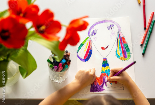 Close-up of girl's hands draw a portrait of mom