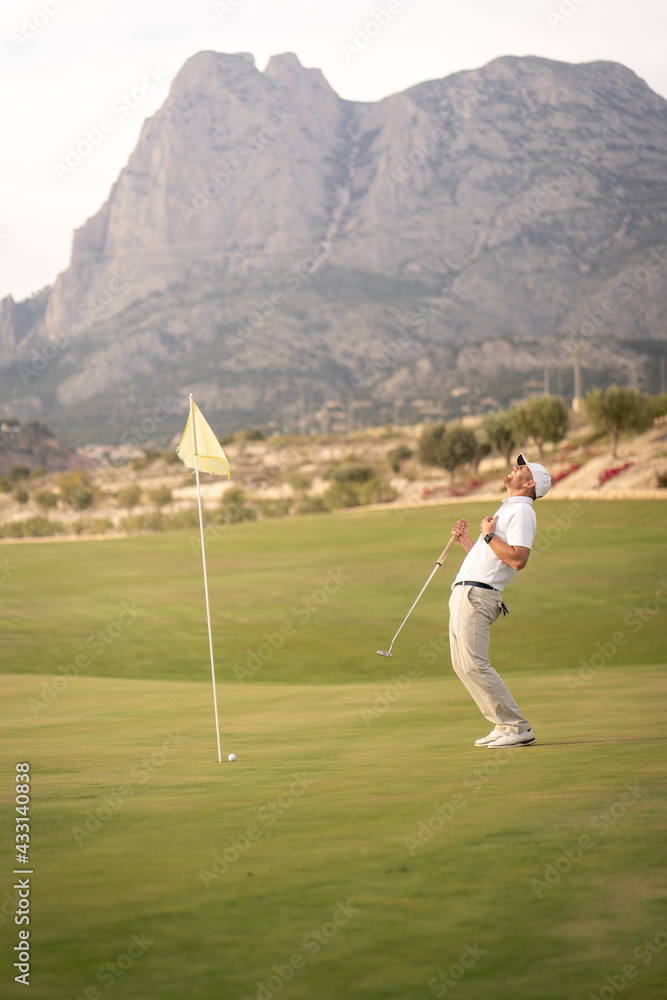 Obraz premium Angry golfer lamenting for missing his shot on the green a few inches from the hole.