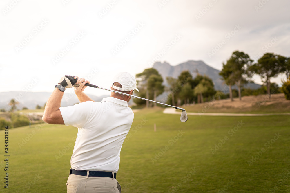Obraz premium Golf player making a perfect swing on the golf course in the sunset.