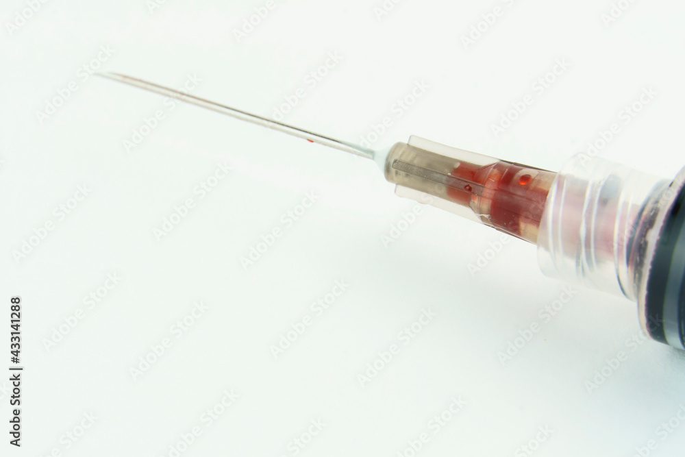 Syringe with a little blood on white background. Selective focus. Macro. Syringe with a little blood on white background. Selective focus. Macro.