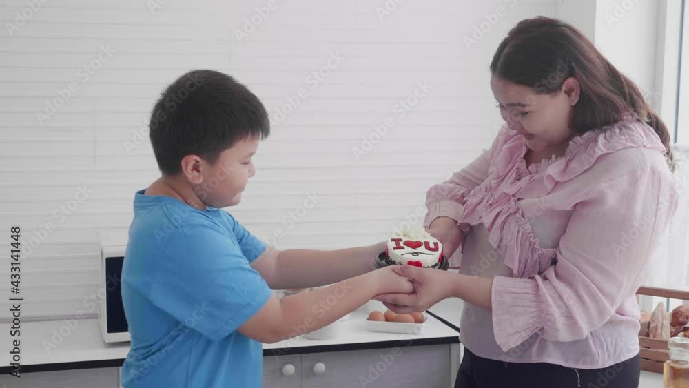 Asian family relationship with son giving cake with mother in birthday and hug at home, happiness boy celebration with mom and embrace in party together, two people, mothers day, holiday concept. Asian family relationship with son giving cake with mother in birthday and hug at home, happiness boy celebration with mom and embrace in party together, two people, mothers day, holiday concept.