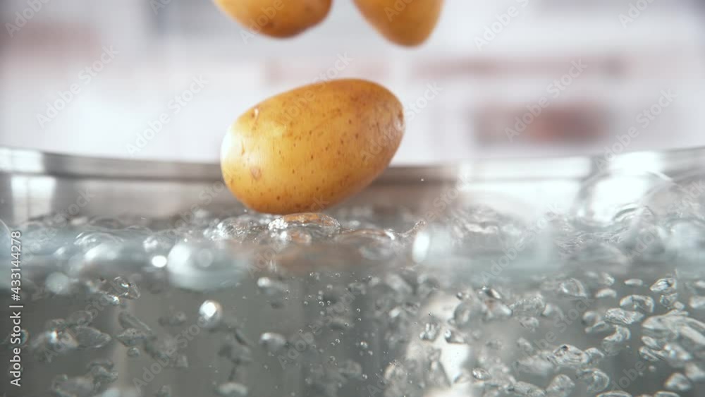 Unpeeled Potatoes Falling into Pot with Boiling Water in Macro and Slow