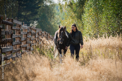 Walking a girl with a horse along the fence at the ranch in the fall