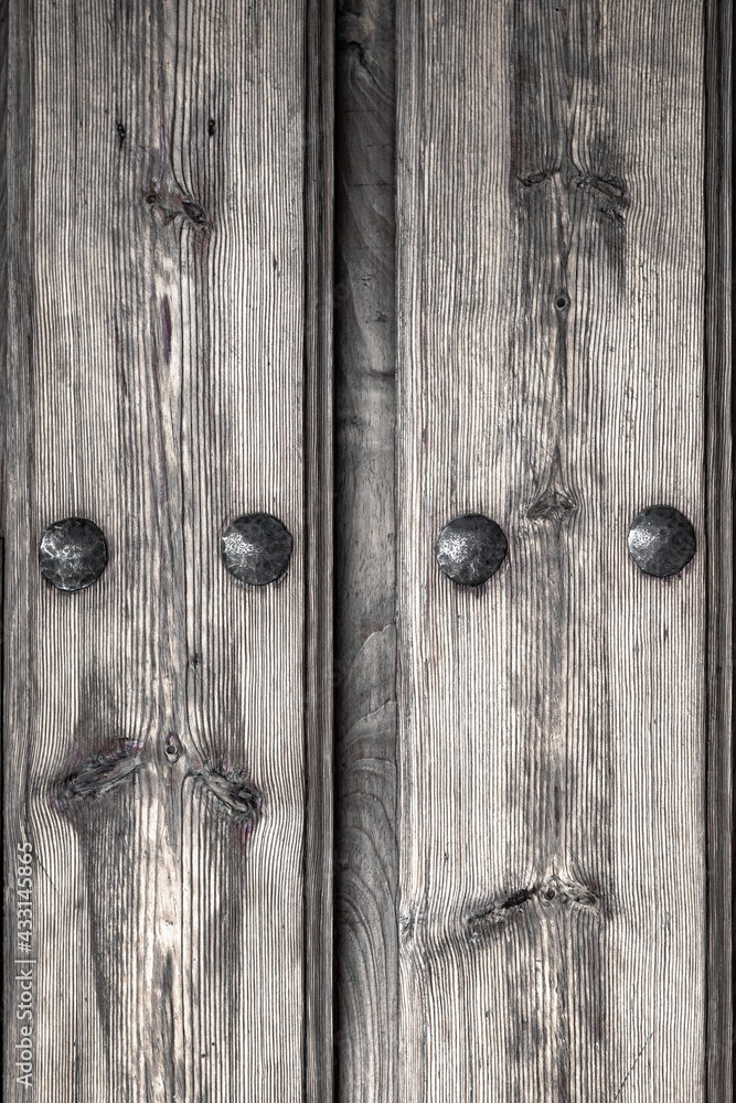 Obraz premium Black and white antique wooden door with nails and knots. Rustic and retro old door full of knots and scratches. Vintage wood texture surface, wood vein. Pareidolia, faces in wood grain.