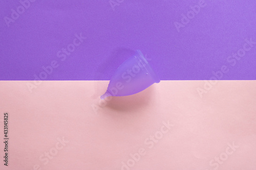 purple menstrual cup on a plain bicolor purple and pink background photo