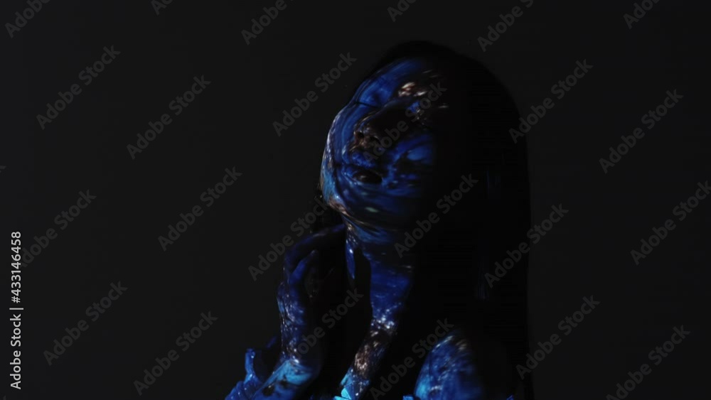 Exotic beauty. Fantasy portrait. Mystic goddess. Universe wisdom. Silhouette of peaceful relaxed alien woman touching blue glitter face in projector light motion isolated on dark. Exotic beauty. Fantasy portrait. Mystic goddess. Universe wisdom. Silhouette of peaceful relaxed alien woman touching blue glitter face in projector light motion isolated on dark.