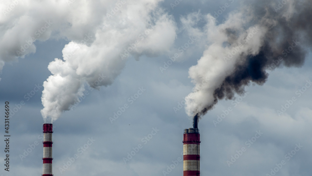 Industrial smoke from chimney on dramatic sky background. View of high chimney pipes with grey smoke from coal power plant. Production of electricity with fossil fuel. Wind blowing pollution. Industrial smoke from chimney on dramatic sky background. View of high chimney pipes with grey smoke from coal power plant. Production of electricity with fossil fuel. Wind blowing pollution.