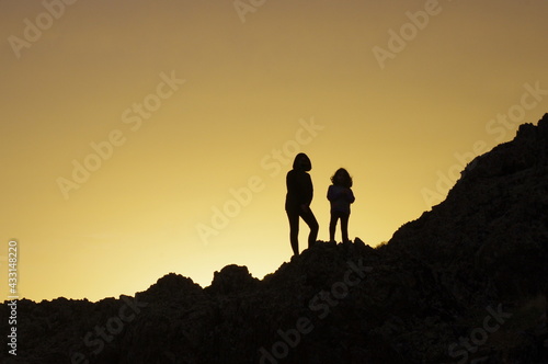 Two sisters watching the sunset on the hill.