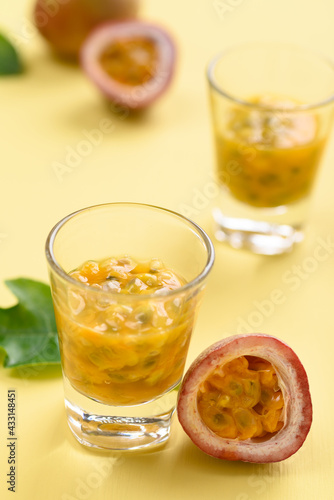 Fresh passion fruit juice in glass on yellow background