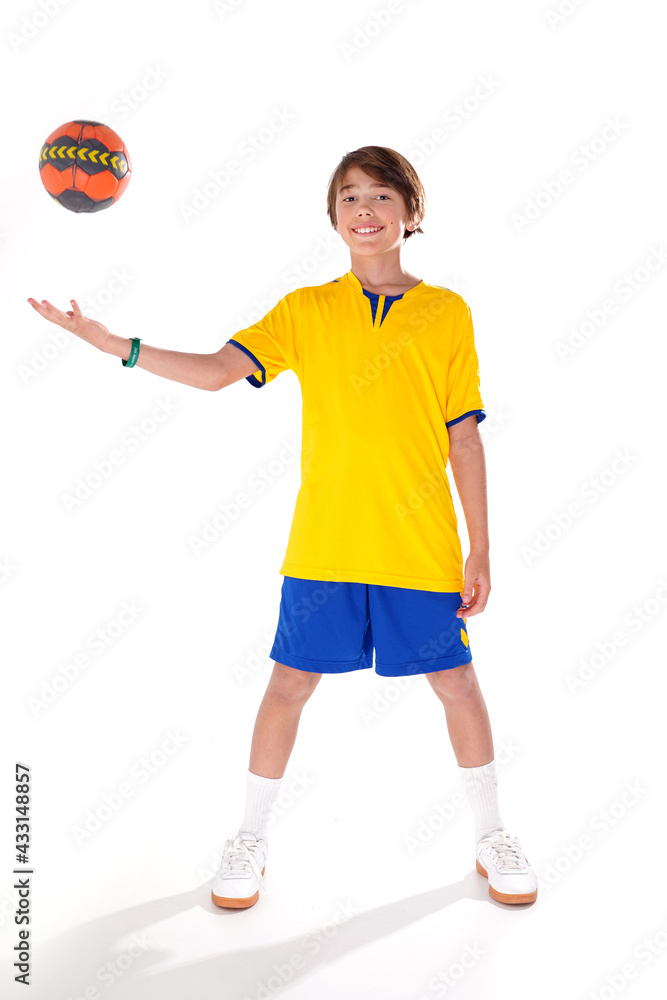 Full length photo of a young sporty boy holding handball and smiling to the camera