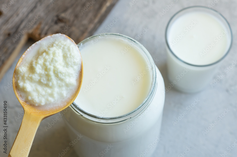 Obraz na płótnie Kefir grains in wooden spoon with glass of kefir drink, healthy fermented probio