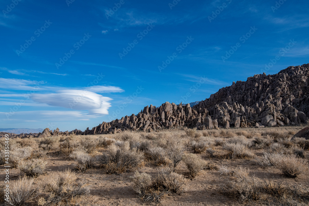 Skyline view of lenticular cloud, mountains, rocks. Alabama Hills, California