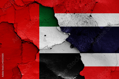 flags of UAE and Thailand painted on cracked wall