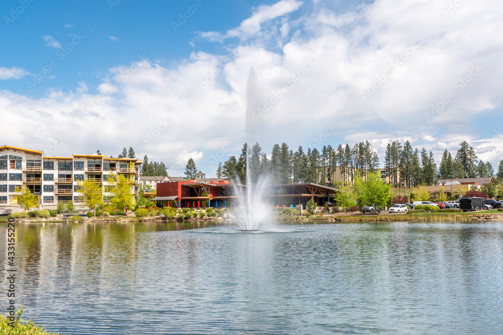 Riverstone public park in Coeur d'Alene, Idaho, USA, with restaurants, new construction and the water fountain spraying in the small lake.