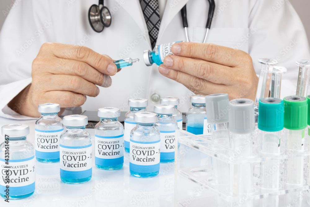 A doctor or a scientist in a laboratory coat holding a syringe with liquid vaccine vial. A doctor or a scientist in a laboratory coat holding a syringe with liquid vaccine vial.