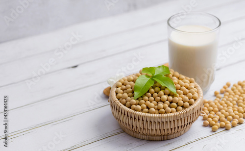 Soy and soy milk in a glass with soybeans in wooden bowl background © Keopaserth
