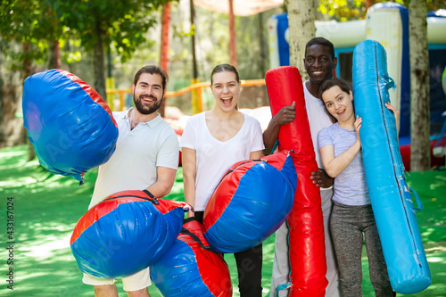 Portrait of happy friends with inflatable logs and pillows at an amusement park photo