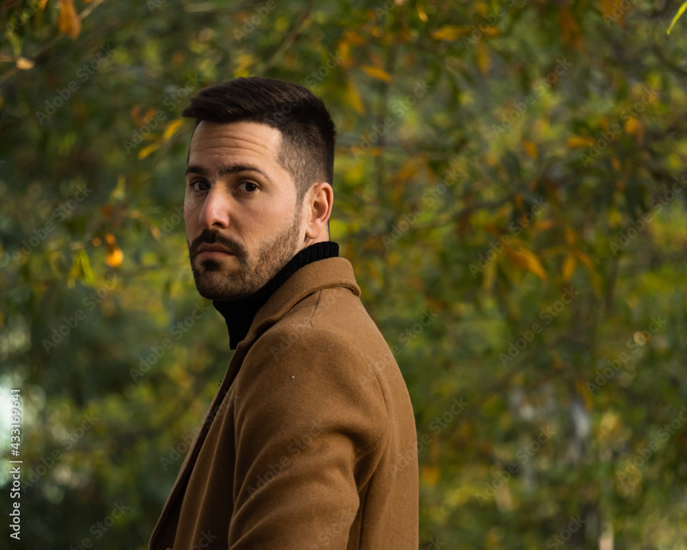 Fall portrait of a bearded man with a brown coat at sunset time in the park Fall portrait of a bearded man with a brown coat at sunset time in the park