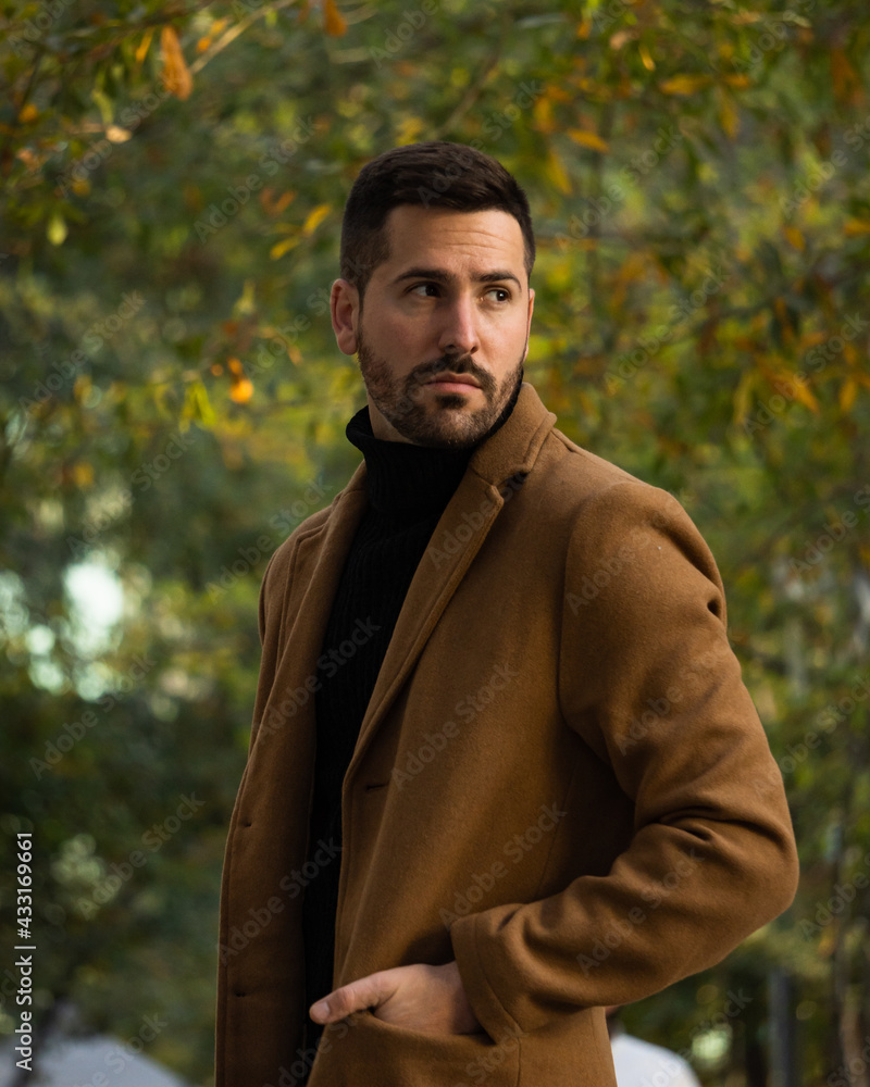 Fall portrait of a bearded man with a brown coat at sunset time in the park Fall portrait of a bearded man with a brown coat at sunset time in the park