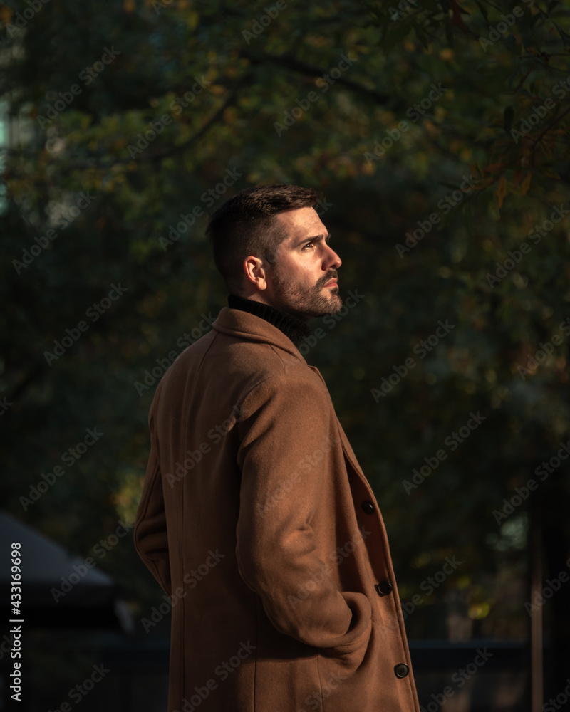Fall portrait of a bearded man with a brown coat at sunset time in the park Fall portrait of a bearded man with a brown coat at sunset time in the park