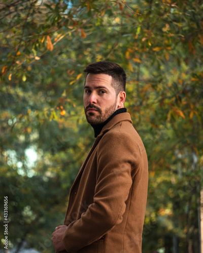 Fall portrait of a bearded man with a brown coat at sunset time in the park