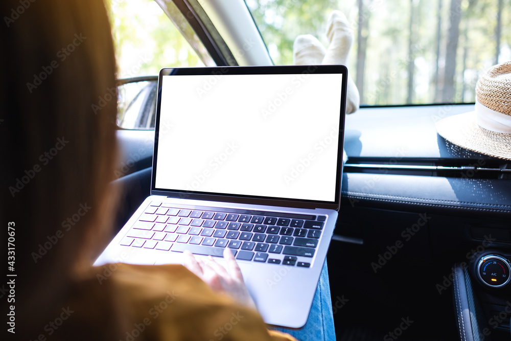 Mockup image of a woman using and typing on laptop computer with blank desktop screen in the car Mockup image of a woman using and typing on laptop computer with blank desktop screen in the car