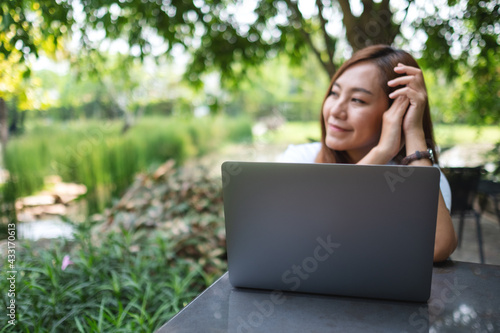 A beautiful young asian woman take a break from working on laptop computer in the park