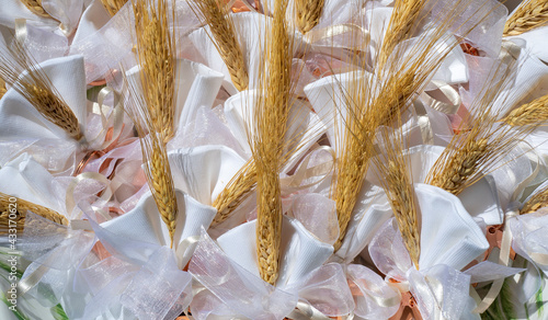 Gifts or favors for the first or holy communion. Small bags of white fabric with ear of wheat and Tau Christian cross. Religious symbol