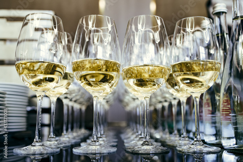 white wine glasses in focus with wine on catering table
