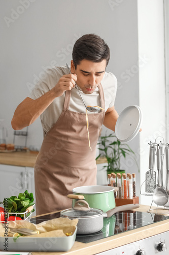 Young man tasting dish in k...