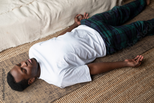 Foto Young black man lying in Dead Body exercise or Corpse pose with his eyes closed,