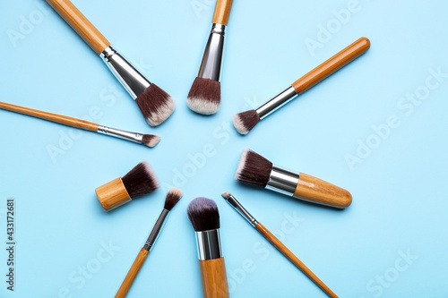 Frame made of makeup brushes on color background