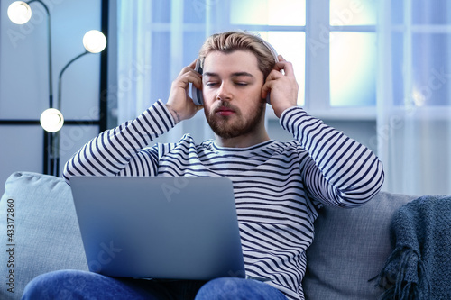 Young man with laptop playi...
