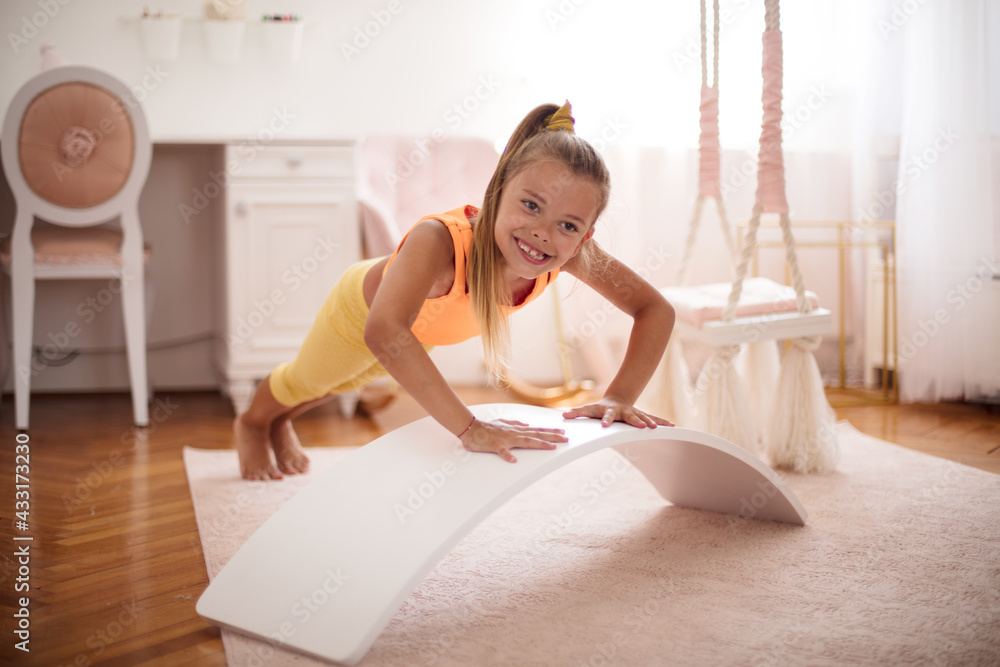 Little girl doing push-ups in the bedroom at home. Little girl doing push-ups in the bedroom at home.
