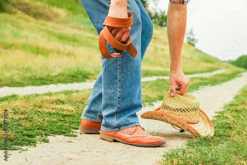 A Cowboy legs in shoes in the park on nature background. The man at the ranch.