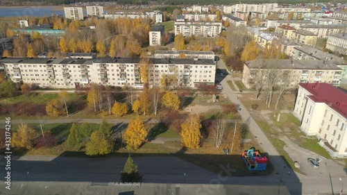 Aerial view of house of culture, alley and pond in a provincial autumn city with old three- and five-story houses. There is a square and a monument in front of the house of culture. Cars drive on the  photo