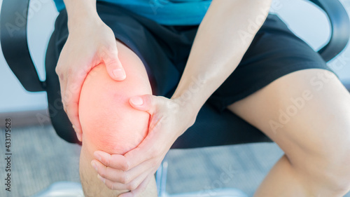 A man grabs the knee of the painful size, the sore spot is highlighted in red.