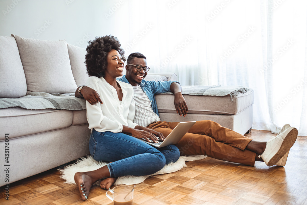Close up of a happy young couple using laptop at home. Young Couple Enjoying Lazy Sunday Using Laptop By the Window. Happy Couple Using Laptop Sitting On Floor Indoor