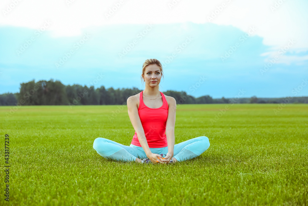 sport woman is doing yoga exercises on large grass field on sunset. sport woman is doing yoga exercises on large grass field on sunset.