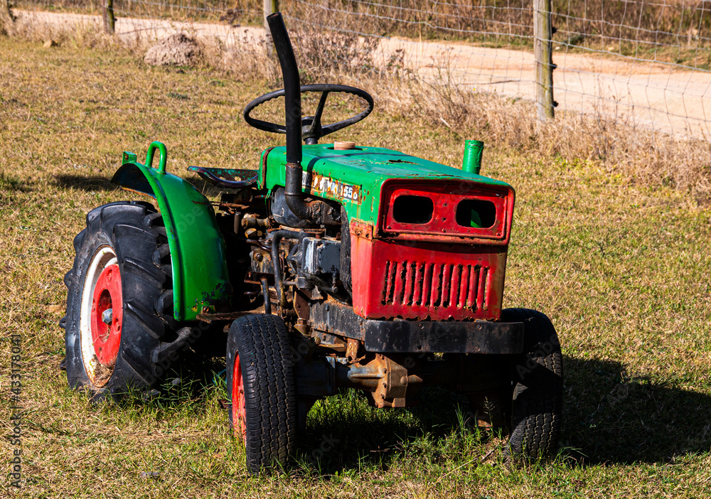 Obraz premium Old Red and Green Farm Tractor in Long Grass