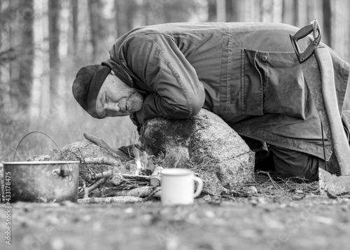black and white photo of a lumberjack in the woods, a man lighting a campfire and making tea, autumn
