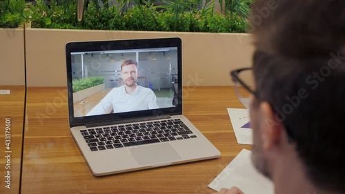 Over shoulder view of male worker have webcam digital virtual conference. Businessman speak talk on video call with manager. Online meeting concept.