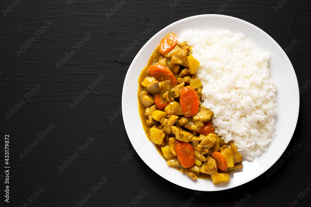 Homemade Japanese Chicken Curry on a white plate on a black background, top view. Flat lay, overhead, from above. Space for text. Homemade Japanese Chicken Curry on a white plate on a black background, top view. Flat lay, overhead, from above. Space for text.