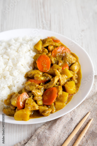 Homemade Japanese Chicken Curry  on a white plate on a white wooden background, side view.