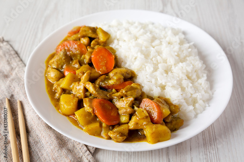 Homemade Japanese Chicken Curry  on a white plate on a white wooden background, side view.