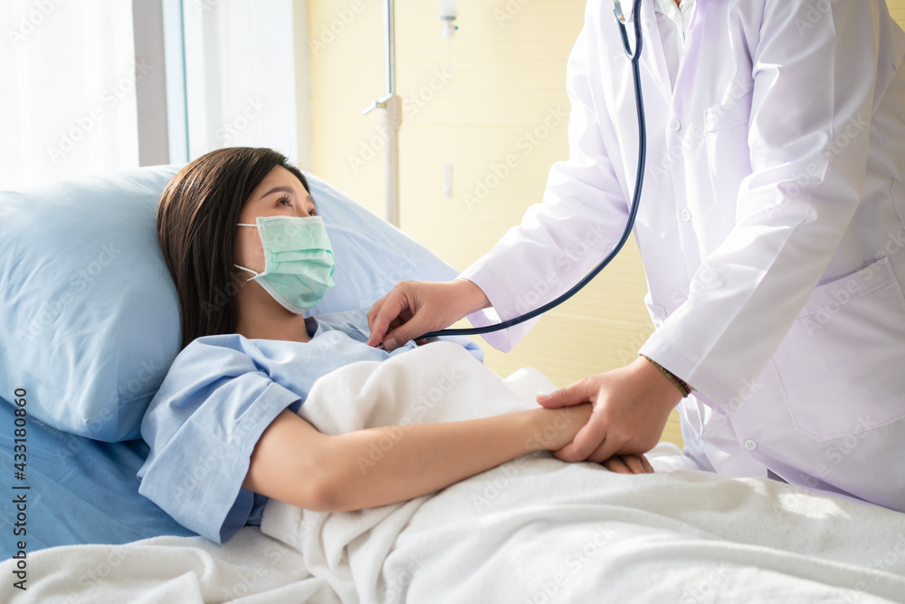 Women Asian doctors hold the patient hand and encourage and provide medical advice While doctors use Stethoscope for checking the patient heart in bed. Concept of Care and compassion Women Asian doctors hold the patient hand and encourage and provide medical advice While doctors use Stethoscope for checking the patient heart in bed. Concept of Care and compassion